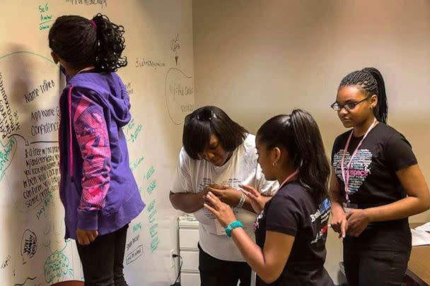 PHOTO: Alumna Azure Butler (right) and other participants are seen engaging in an activity alongside Black Girls CODE leadership in the program's earlier days of the Bay Area chapter in California. (Black Girls CODE)