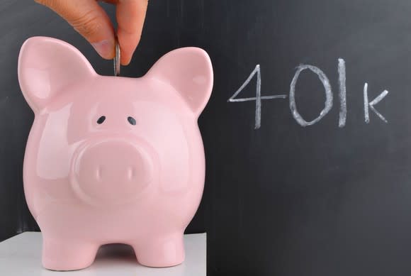 Coin being inserted into a piggy bank next to the term 401k written in on a chalkboard