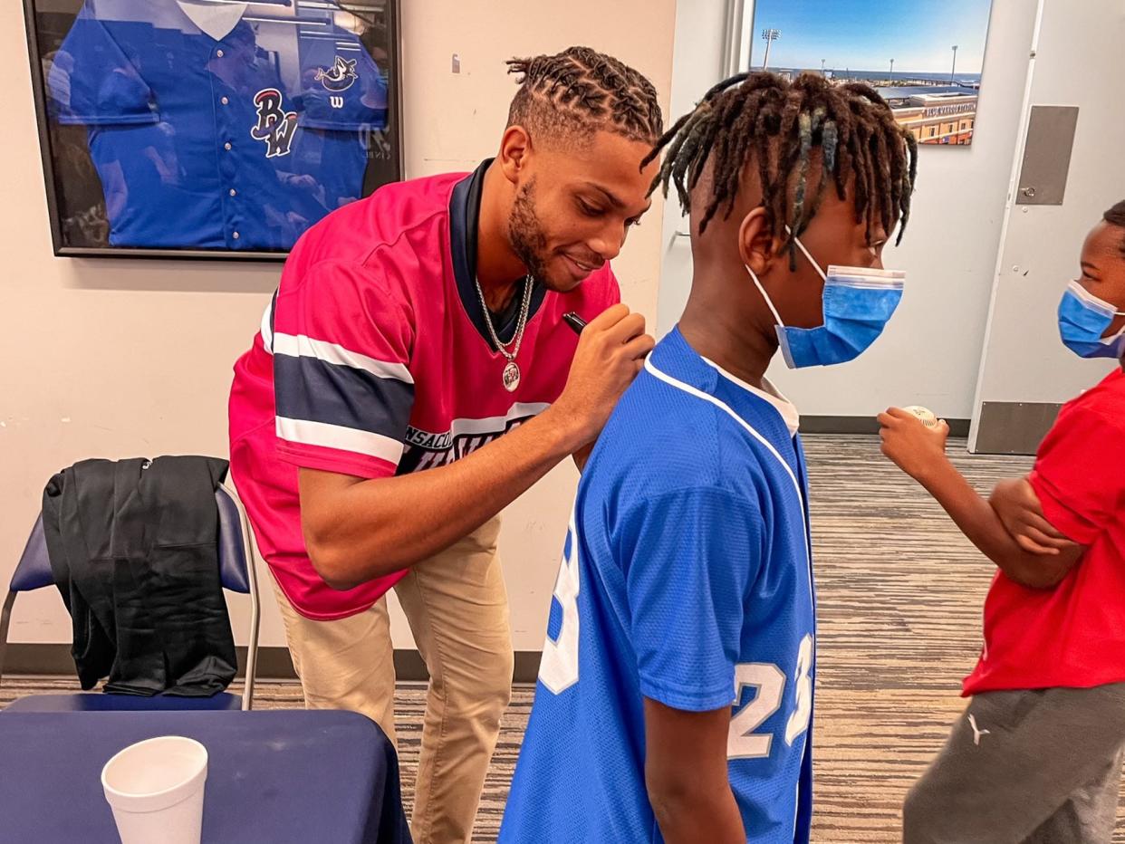 Marlins' Jordan McCants signing a young fan's jersey during the Pensacola Blue Wahoos' Fish Fest event.