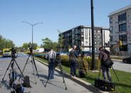 Members of the media wait outside a condo building in Longueil