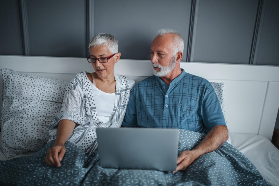 Senior couple in bed with laptop