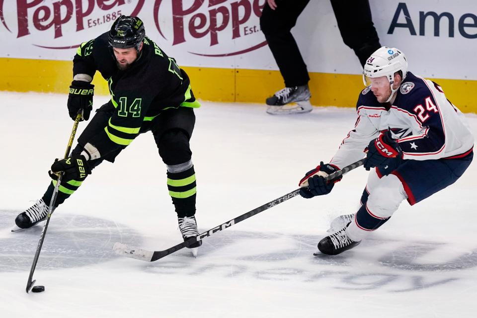 Dallas Stars left wing Jamie Benn (14) tries to control the puck against Columbus Blue Jackets right wing Mathieu Olivier (24) during the third period of an NHL hockey game in Dallas, Saturday, Feb. 18, 2023. The Blue Jackets won 4-1. (AP Photo/LM Otero)