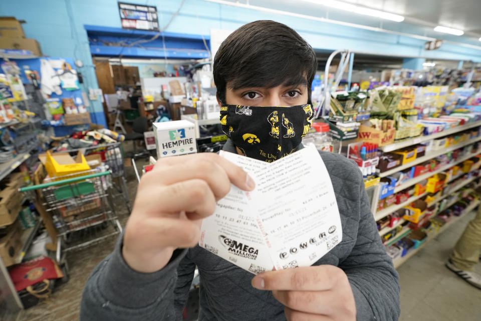 Hardik Kalra, of Des Moines, Iowa, poses for a photo with his Mega Millions and Powerball lottery tickets, Tuesday, Jan. 12, 2021, in Des Moines, Iowa. (AP Photo/Charlie Neibergall)