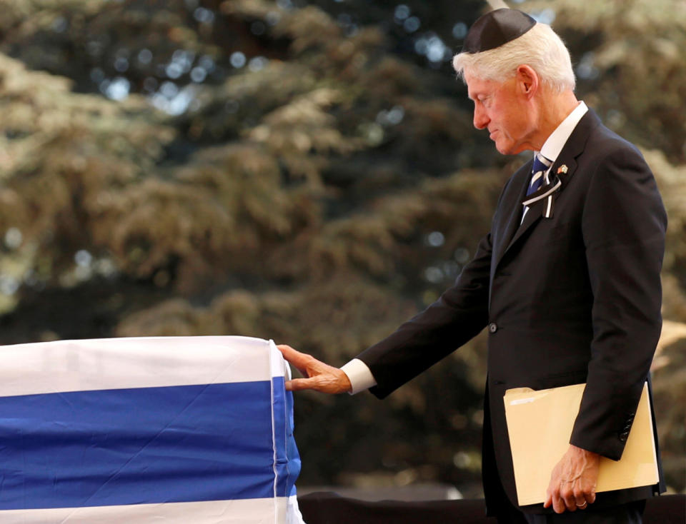 <p>Former President Bill Clinton touches the flag-draped coffin of former Israeli President Shimon Peres, after eulogizing him during his funeral ceremony at Mount Herzl cemetery in Jerusalem on Sept. 30, 2016.(REUTERS/Kevin Lamarque)</p>