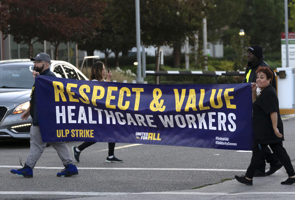 Kaiser Permanente workers carry a sign outside the hospital during a protest strike in the Panorama City section of Los Angeles on Wednesday, Oct. 4, 2023. Picketing has begun at Kaiser Permanente hospitals as some 75,000 workers who say understaffing is hurting patient care go on strike in five states and the District of Columbia. It marks the latest major labor unrest in the U.S. Kaiser Permanente is one of the country's larger insurers and health care system operators. (AP Photo/Richard Vogel)