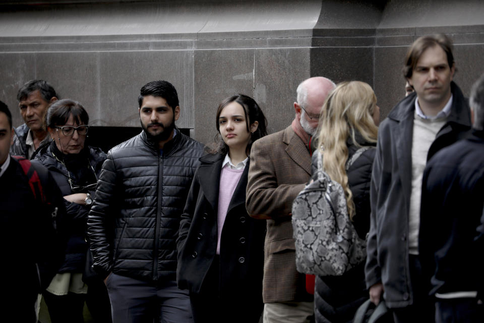 People wait for a bank to open in Buenos Aires, Argentina, Monday, Sept. 2, 2019. Some Argentines withdrew their savings from banks this past week amid fears of a default, ahead of Sunday's government decree that Argentines will need authorization from the central bank for the rest of the year to buy U.S. dollars in some cases and make transfers abroad as it tries to prop up its peso currency. (AP Photo/Natacha Pisarenko)