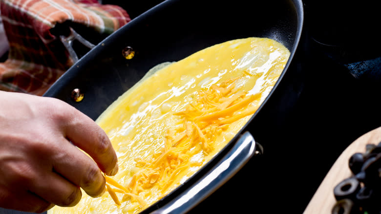 sprinkling cheese on omelet