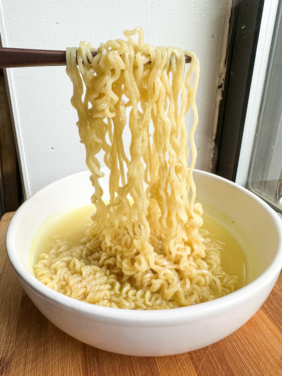 chopstick holding up instant top ramen noodles