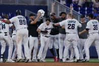 Teammates mob Miami Marlins' Brian Anderson, center, after Anderson tripled scoring Jesus Aguilar and Avisail Garcia during the 11th inning of a baseball game against the Pittsburgh Pirates, Thursday, July 14, 2022, in Miami. (AP Photo/Wilfredo Lee)