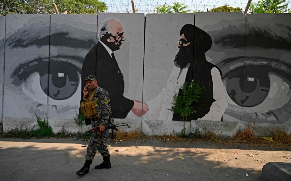 A security personnel walks past a wall mural with images of US Special Representative for Afghanistan Reconciliation Zalmay Khalilzad (L) and Taliban co-founder Mullah Abdul Ghani Baradar, in Kabul  - AFP/AFP