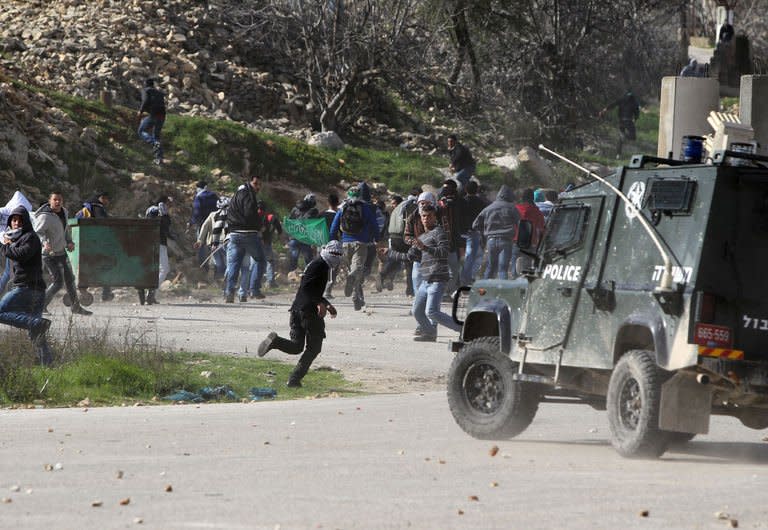 Palestinian protesters throw stones towards an Israeli police vehicle during clashes in front of Ofer prison, near the West Bank city of Ramallah, on February 15, 2013. Thousands rallied in the West Bank's two largest cities on Monday in support of four long-term hunger strikers, as the Palestinians demanded tougher EU action to help their prisoners