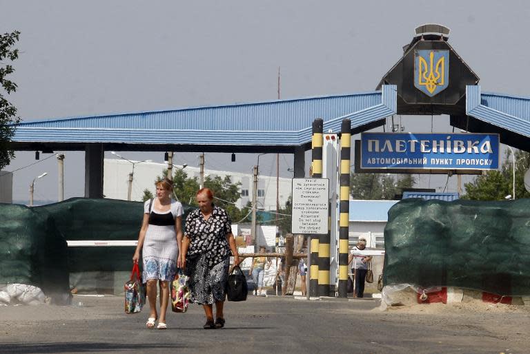 People cross the border at the checkpoint of Pletnyovka on the Ukraine-Russia border, where a Russian humanitarian convoy is to cross, on August 13, 2014