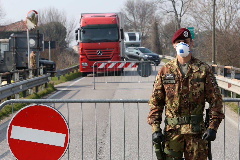 An Italian Army officer wearing a protective face mask stands at a roadblock at the entrance to the small town of Vo as Italy closes down. Source: AAP