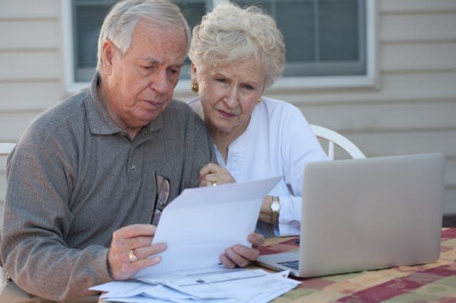 Senior couple working on home / personal finance using laptop with concerned expression