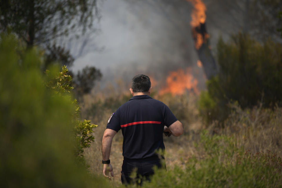 A fireman approaches a fire in a forest near Le Luc, southern France, Tuesday, Aug. 17, 2021. Thousands of people were evacuated from homes and vacation spots near the French Riviera as firefighters battled a fire racing through surrounding forests Tuesday, the latest of several wildfires that have swept the Mediterranean region. (AP Photo/Daniel Cole)