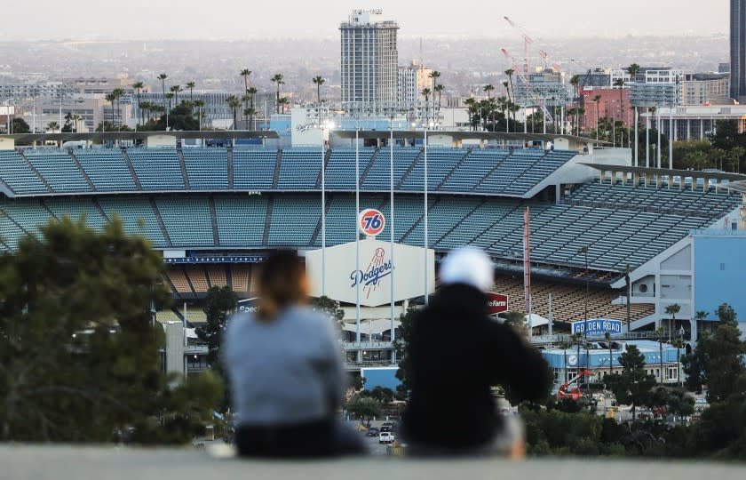 LOS ANGELES, CALIFORNIA - MARCH 26: People sit on a hill overlooking Dodger Stadium on what was supposed to be Major League Baseball's opening day, now postponed due to the coronavirus, on March 26, 2020 in Los Angeles, California. The Los Angeles Dodgers were slated to play against the San Francisco Giants at the stadium today. Major League Baseball Commissioner Rob Manfred recently said the league is "probably not gonna be able to" play a full 162 game regular season due to the spread of COVID-19. (Photo by Mario Tama/Getty Images)