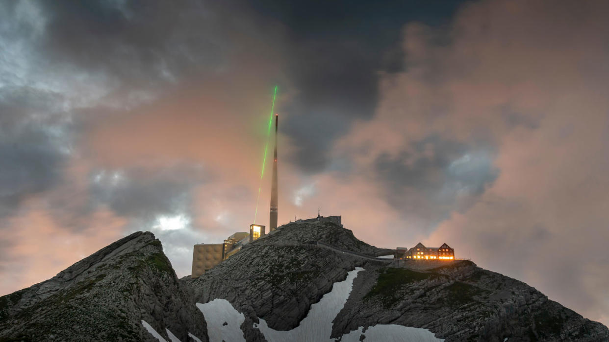  The infrared laser beam fires into the sky above Switzerland's Säntis mountain. 