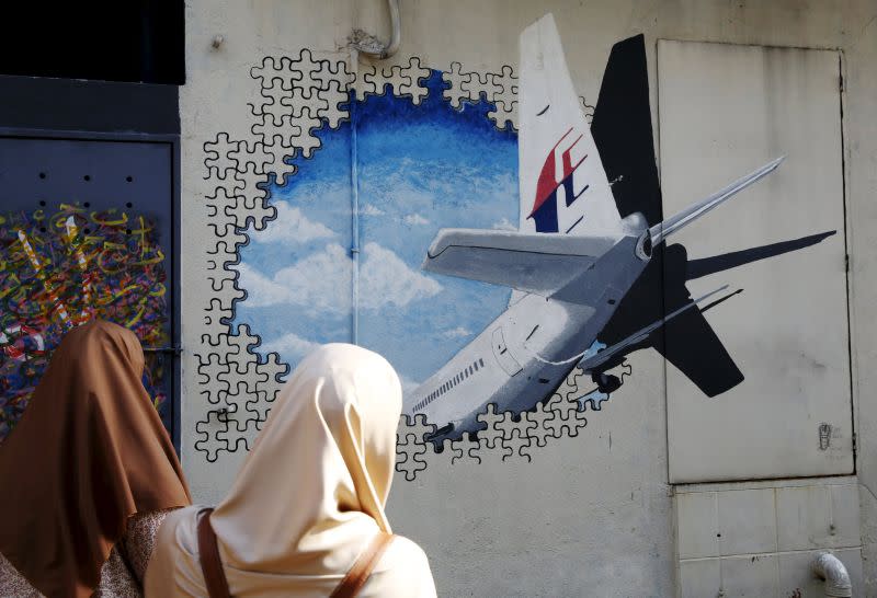 Women look at a mural of missing Malaysia Airlines flight MH370 two years after it disappeared, in Kuala Lumpur, March 8, 2016. ― Reuters pic