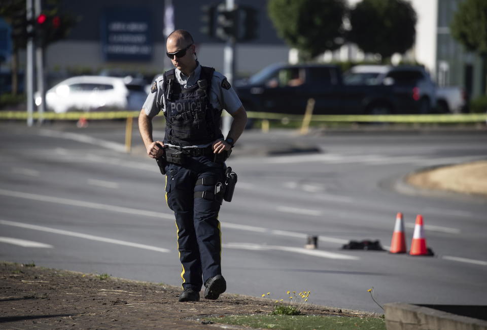 An RCMP officer stands on a median at the scene of a shooting in Langley, British Columbia, Monday, July 25, 2022. Canadian police reported multiple shootings of homeless people Monday in a Vancouver suburb and said a suspect was in custody. (Darryl Dyck/The Canadian Press via AP)