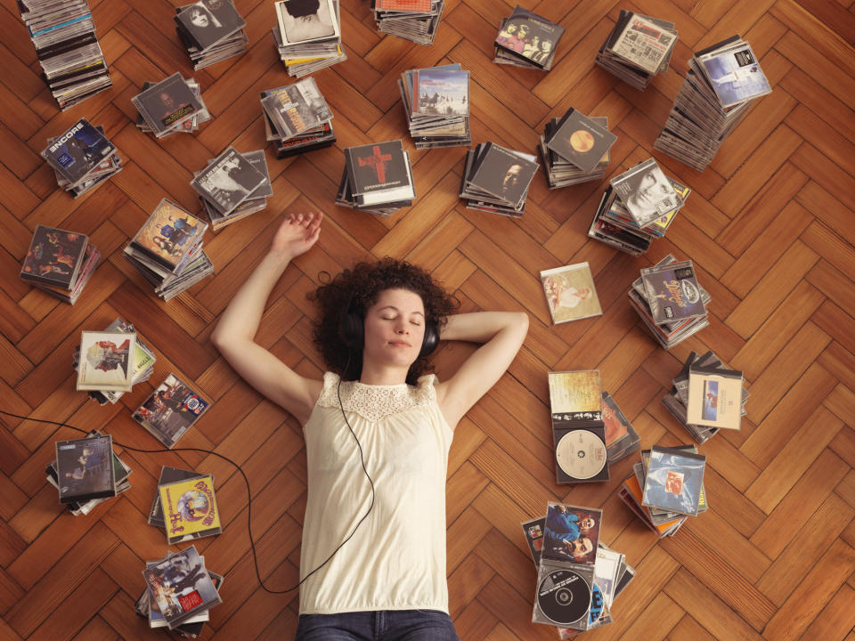 person lying on the floor surrounded by stacks of cds