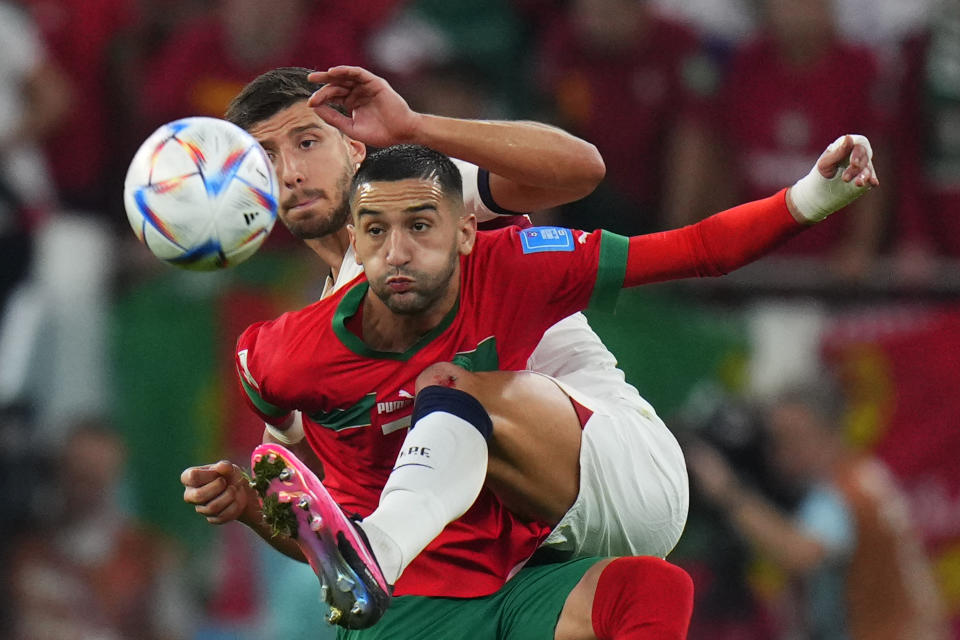 Morocco's Hakim Ziyech, foreground, fights for the ball with Portugal's Ruben Dias during the World Cup quarterfinal soccer match between Morocco and Portugal, at Al Thumama Stadium in Doha, Qatar, Saturday, Dec. 10, 2022. (AP Photo/Petr David Josek)