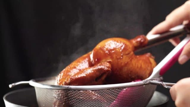 Removing cooked braised soy sauce chicken from pot