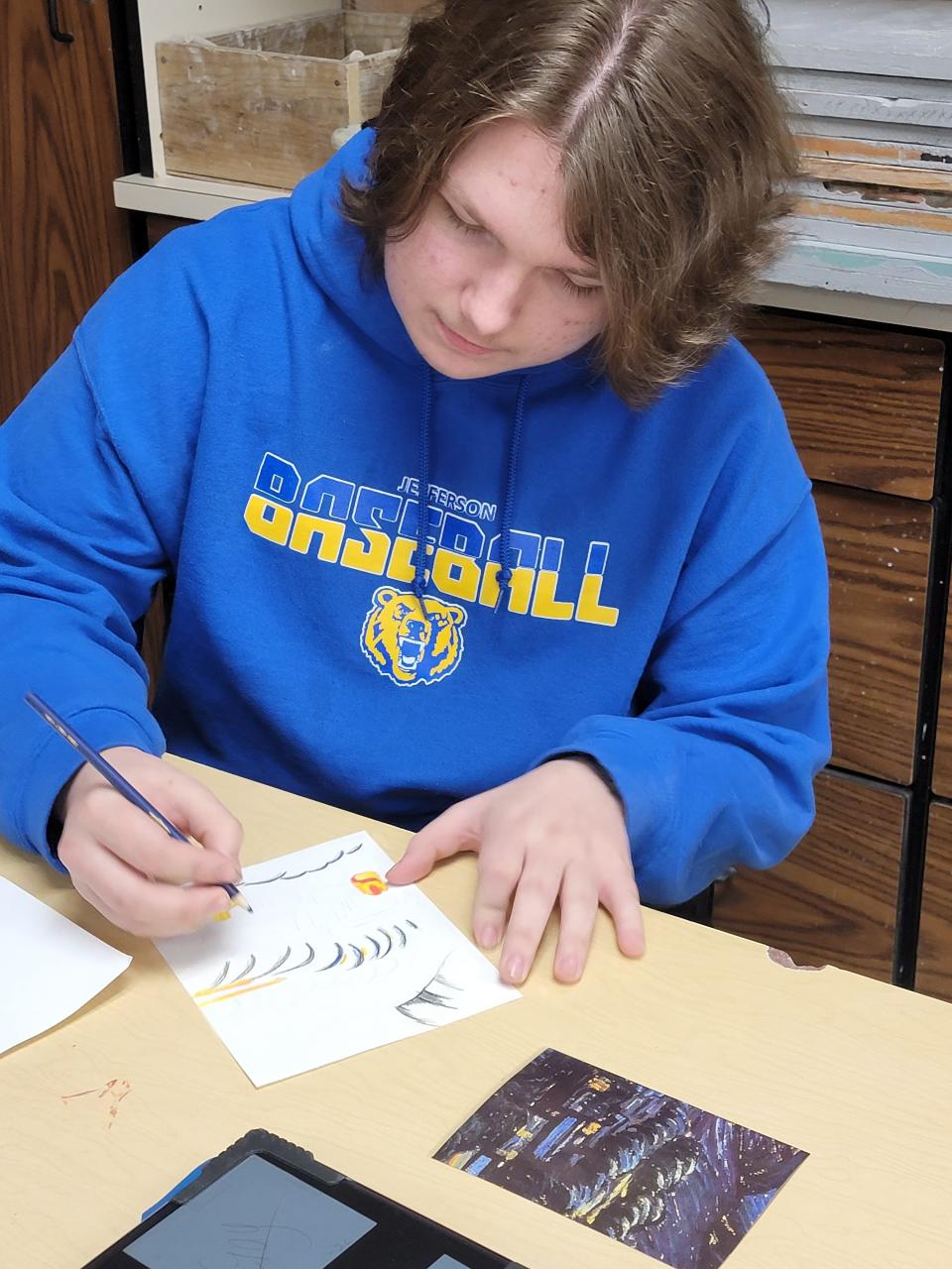 Jefferson High School student Parker Pauwels uses a colored pencil to create a panel for a mixed media art project.