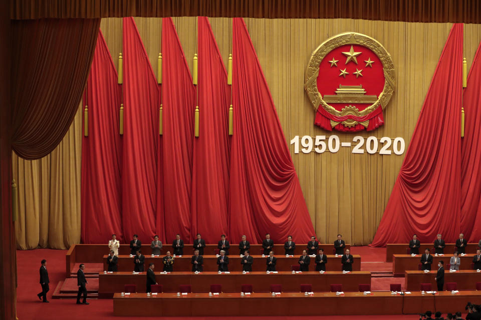 Party officials applaud as Chinese President Xi Jinping, third from left in front row, followed by Premier Li Keqiang, arrives for the commemorating conference on the 70th anniversary of the Chinese army entering North Korea to resist the US army, at the Great Hall fo the People in Beijing, Friday, Oct. 23, 2020. (AP Photo/Andy Wong)