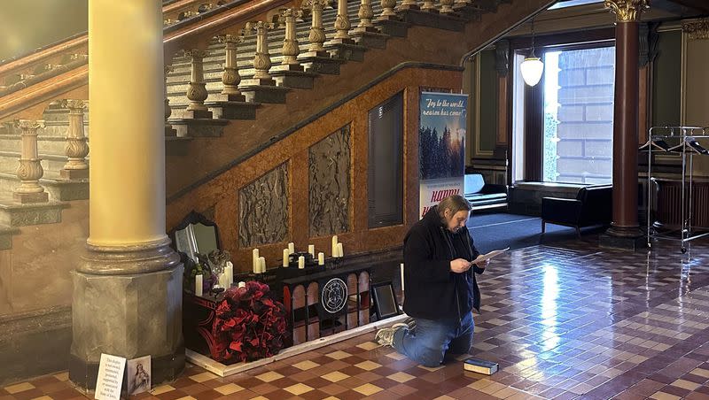 A man recites Christian prayers at a damaged Satanic display at the Iowa state Capitol on Friday, Dec. 15, 2023, in Des Moines, Iowa. The display, which has prompted outrage by some people who say it’s inappropriate at any time but especially during the Christmas holidays, was damaged in December. 