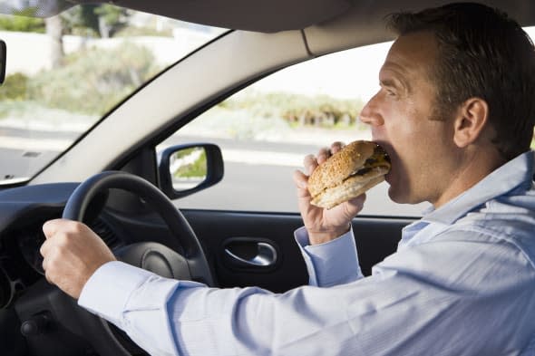Man eating and driving car