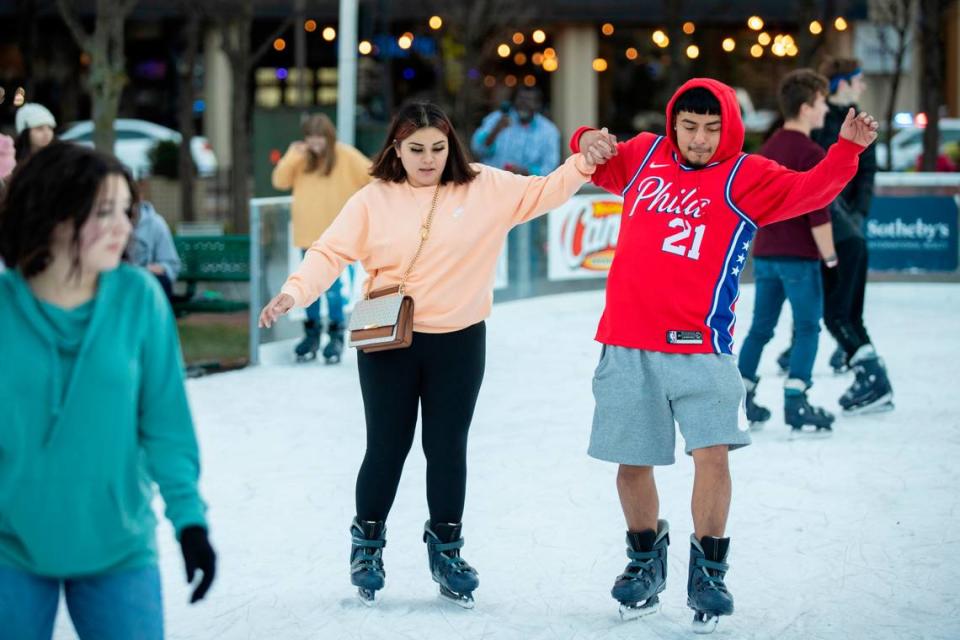 Joselyn Arteaga and Christopher Bravo held hands while ice skating at Triangle Park during the holiday festival Sunday night.