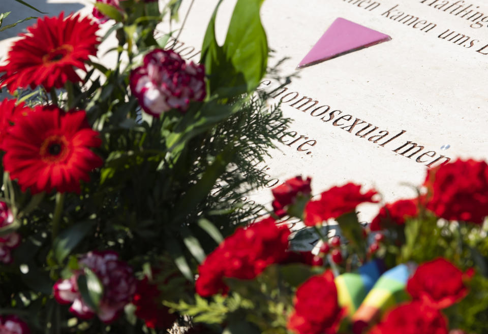 Flowers are placed at a memorial stone in remembrance for prisoners assigned a pink triangle in the former Nazi concentration camp Buchenwald within the Christopher Street Day in Weimar, Germany, Sunday, June 23, 2019. There were 650 prisoners assigned a pink triangle in the Buchenwald concentration camp between 1937 and 1945. Many of them lost their lives. (AP Photo/Jens Meyer)