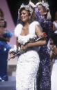 <p>As the '80s went on, the glamour only intensified. Susan Akin from Mississippi did not hold back in this white, embroidered look with fur straps.</p>