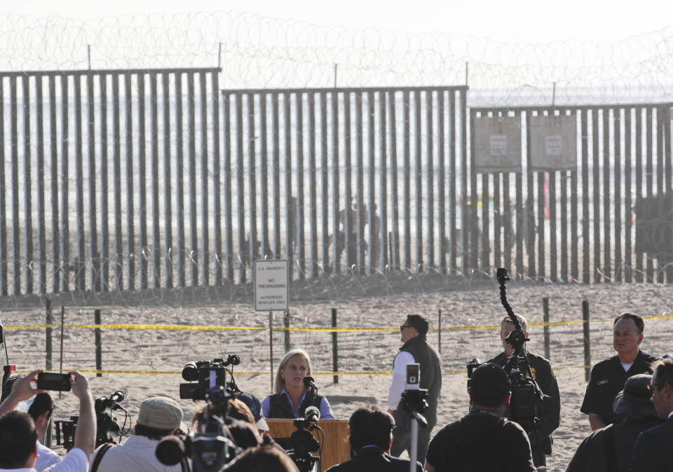 U.S. Homeland Security Secretary Kirstjen Nielsen, below center, speaks in front of the border wall separating Tijuana, Mexico, and San Diego, Tuesday, Nov. 20, 2018, in San Diego. Nielsen said Tuesday an appeal will be filed on the decision by a judge to bar the Trump administration from refusing asylum to migrants who cross the southern border illegally. (AP Photo/Gregory Bull)