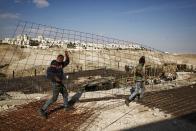 Workers carry material at a construction site in the West bank settlement of Maaleh Adumim, Sunday, Jan. 22, 2017. The municipality of Jerusalem has granted final approval for the construction of hundreds of new homes in east Jerusalem, while a hard-line Cabinet minister pushed the government to annex Maaleh Adumim, a major West Bank settlement as emboldened Israeli nationalists welcomed the presidency of Donald Trump. The building plans were put on hold in the final months of President Barack Obama's administration. (AP Photo/Mahmoud Illean)