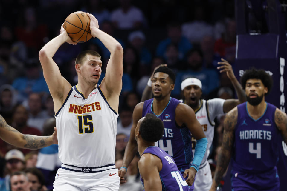 Denver Nuggets center Nikola Jokic (15) look to pass the ball as Charlotte Hornets guard Ish Smith defends during the first half of an NBA basketball game in Charlotte, N.C., Saturday, Dec. 23, 2023. (AP Photo/Nell Redmond)