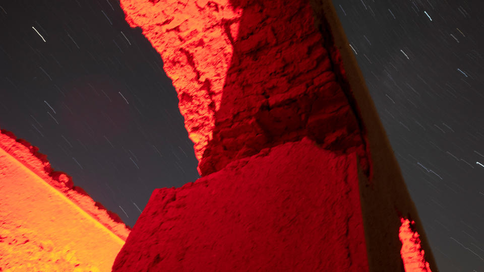 A view of an abandoned historic caravanserai and night sky during Perseid meteor shower.