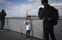 A father takes a photo of his daughter on the ferry coming back from the Statue of Liberty in New York, October 13, 2013. REUTERS/Carlo Allegri