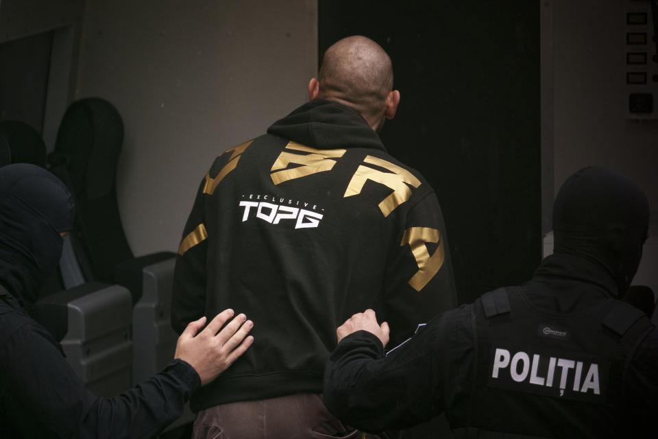 Police officers escort Andrew Tate, center, in a police van outside the Court of Appeal in Bucharest, Romania, Tuesday, March 12, 2024. Online influencer Andrew Tate was detained in Romania and handed an arrest warrant issued by British authorities, his spokesperson said Tuesday. (AP Photo/Andreea Alexandru)