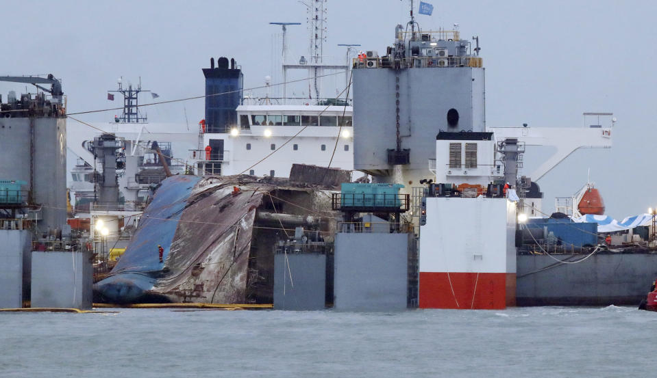 The sunken Sewol ferry is loaded onto a semi-submersible transport vessel during the salvage operation in waters off Jindo, South Korea, Saturday, March 25, 2017. Salvage crews towed the corroded 6,800-ton South Korean ferry toward a transport vessel on Friday after it was successfully raised from waters off the country's southwest coast. The massive attempt to bring the ferry back to shore, nearly three years after it sank, killing 304 people, is being closely watched by a nation that still vividly remembers the horrific accident. (Lee Jin-wook/Yonhap via AP)