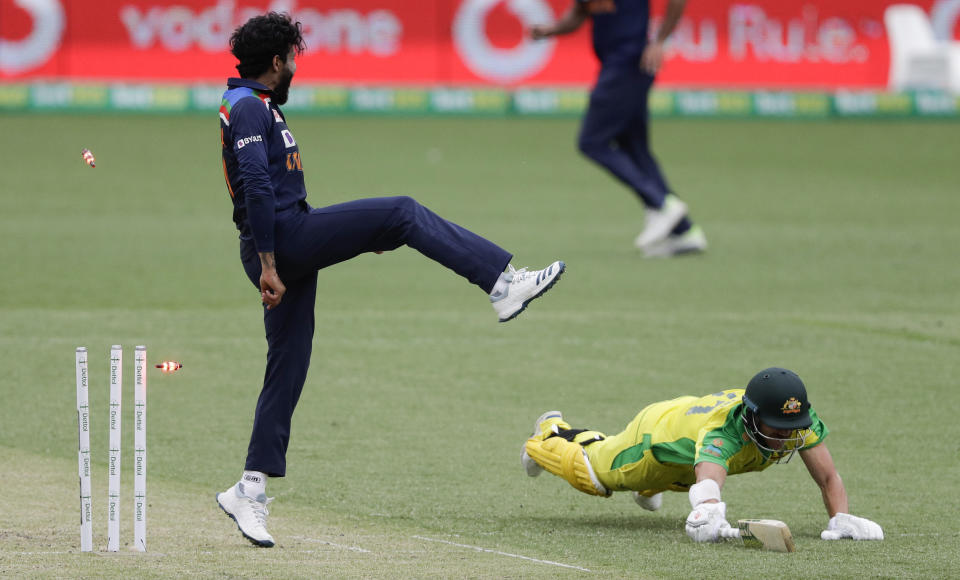 The bails fly as Australia's David Warner, right, is run out as India's Ravindra Jadeja leaps clear of the ball during the one day international cricket match between India and Australia at the Sydney Cricket Ground in Sydney, Australia, Sunday, Nov. 29, 2020. (AP Photo/Rick Rycroft)