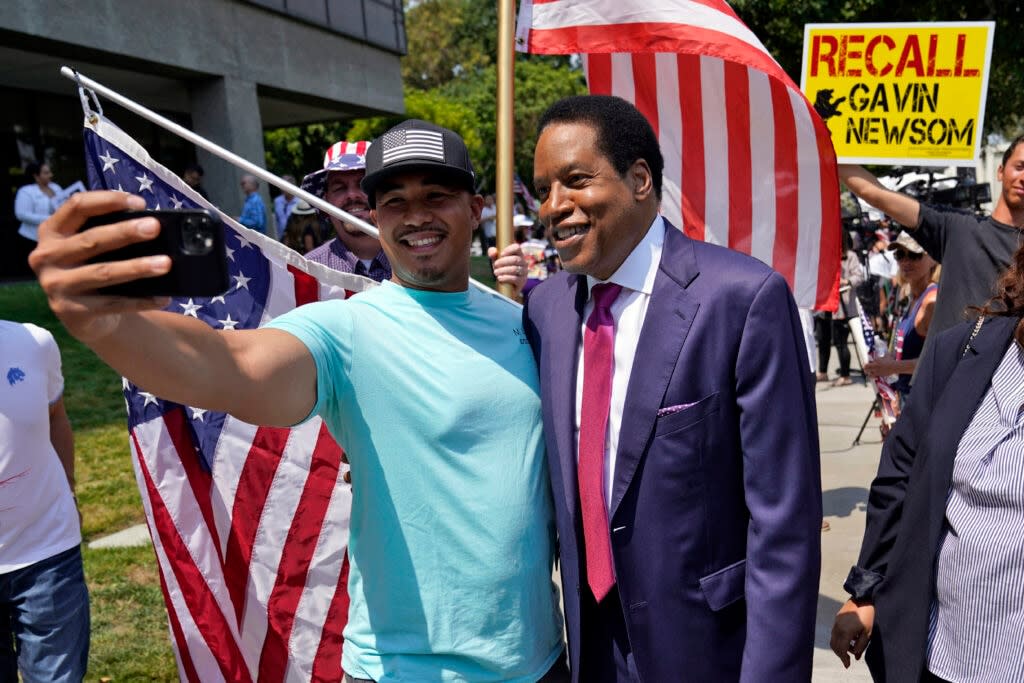 Radio talk show host Larry Elder, center, poses for selfies with supporters during a campaign stop in Norwalk, Calif. (AP Photo/Marcio Jose Sanchez, File)