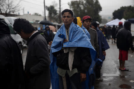 Migrants, part of a caravan of thousands from Central America trying to reach the United States, line up for a food distribution at a temporary shelter during heavy rainfall in Tijuana, Mexico, November 29, 2018. REUTERS/Alkis Konstantinidis