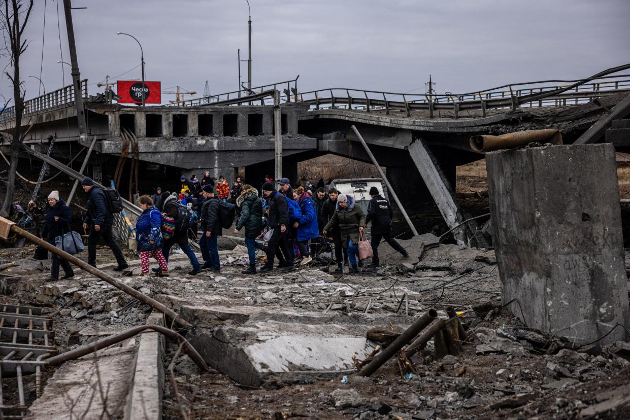 Evacuees cross a destroyed bridge as they flee the city of Irpin, northwest of Kyiv, on March 7, 2022. - Ukraine dismissed Moscow's offer to set up humanitarian corridors from several bombarded cities on Monday after it emerged some routes would lead refugees into Russia or Belarus. The Russian proposal of safe passage from Kharkiv, Kyiv, Mariupol and Sumy had come after terrified Ukrainian civilians came under fire in previous ceasefire attempts. (Photo by Dimitar DILKOFF / AFP) (Photo by DIMITAR DILKOFF/AFP via Getty Images)