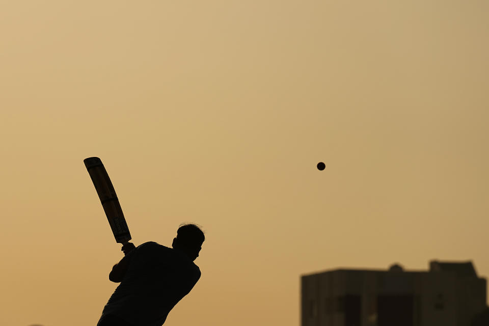 People play cricket in the streets in Doha, Qatar, Friday, Nov. 25, 2022. As dawn broke Friday as Qatar hosts the World Cup, the laborers who built this energy-rich country's stadiums, roads and rail filled empty stretches of asphalt and sandlots to play cricket. (AP Photo/Abbie Parr)