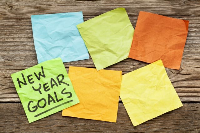 New Year goals - handwriting on a sticky note against grained wood with blank notes