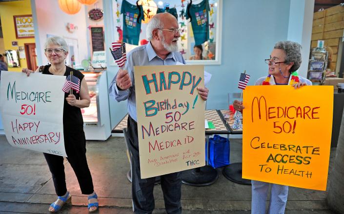 Susan Veale, from left, Walter Davis and Jackie Shrago hold signs to celebrate the 50th anniversary of Medicare and Medicaid at the Nashville Farmers' Market.