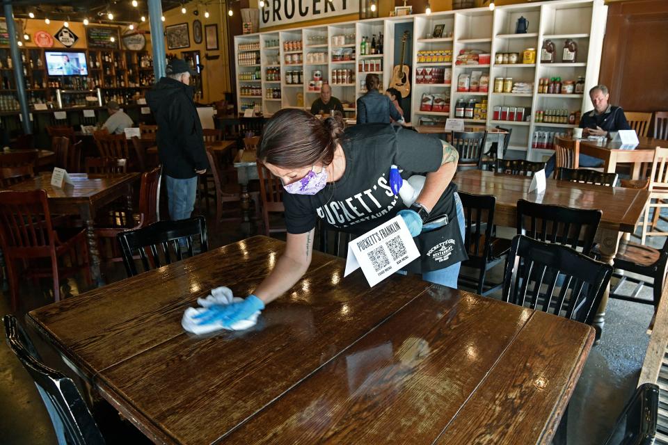 A server at Puckett’s wipes down tables and chairs after customers left. Puckett’s opened on Monday, April 27, 2020, at 50% capacity in Williamson County.