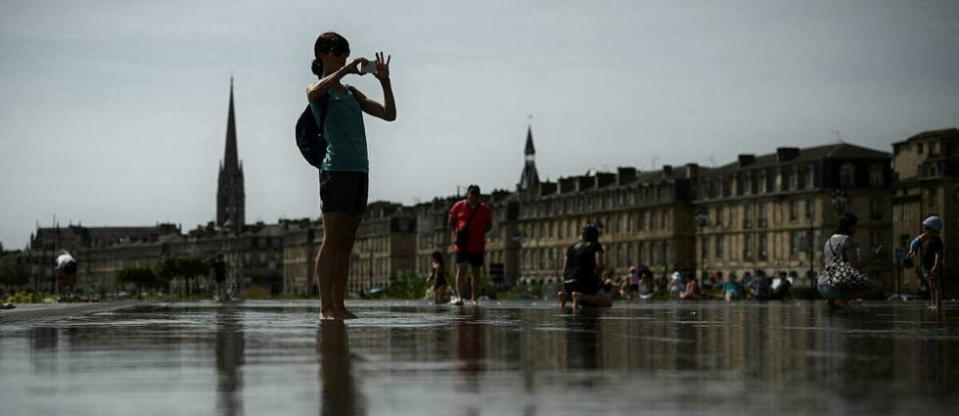 Une femme prend une photo au Miroir d'Eau, à Bordeaux, dans le sud-ouest de la France, le 18 mai 2022.
