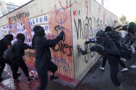 Women attack a wooden wall protecting Mexico's Revolution monument during a march to commemorate International Women's Day and protest against gender violence, in Mexico City, Monday, March 8, 2021. (AP Photo/Rebecca Blackwell)